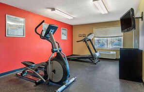 Un gimnasio con cintas de correr, elíptica y un banco de pesas.