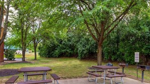 Un parque con mesas de picnic y un letrero.