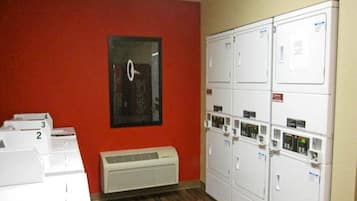 A laundry room with stacked dryers, a wall-mounted clock, and a vent unit.
