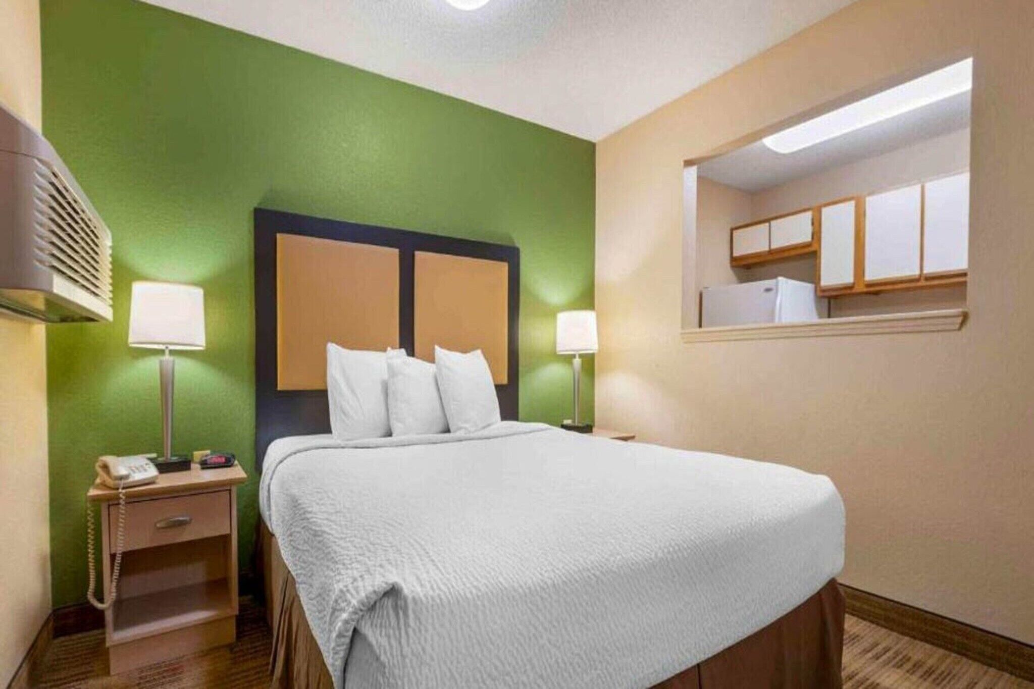 Une chambre d’hôtel avec un lit, des lampes de chevet, une table de chevet avec un téléphone et un miroir.