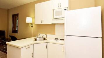 A compact kitchen with a microwave, refrigerator, sink, and cabinets.