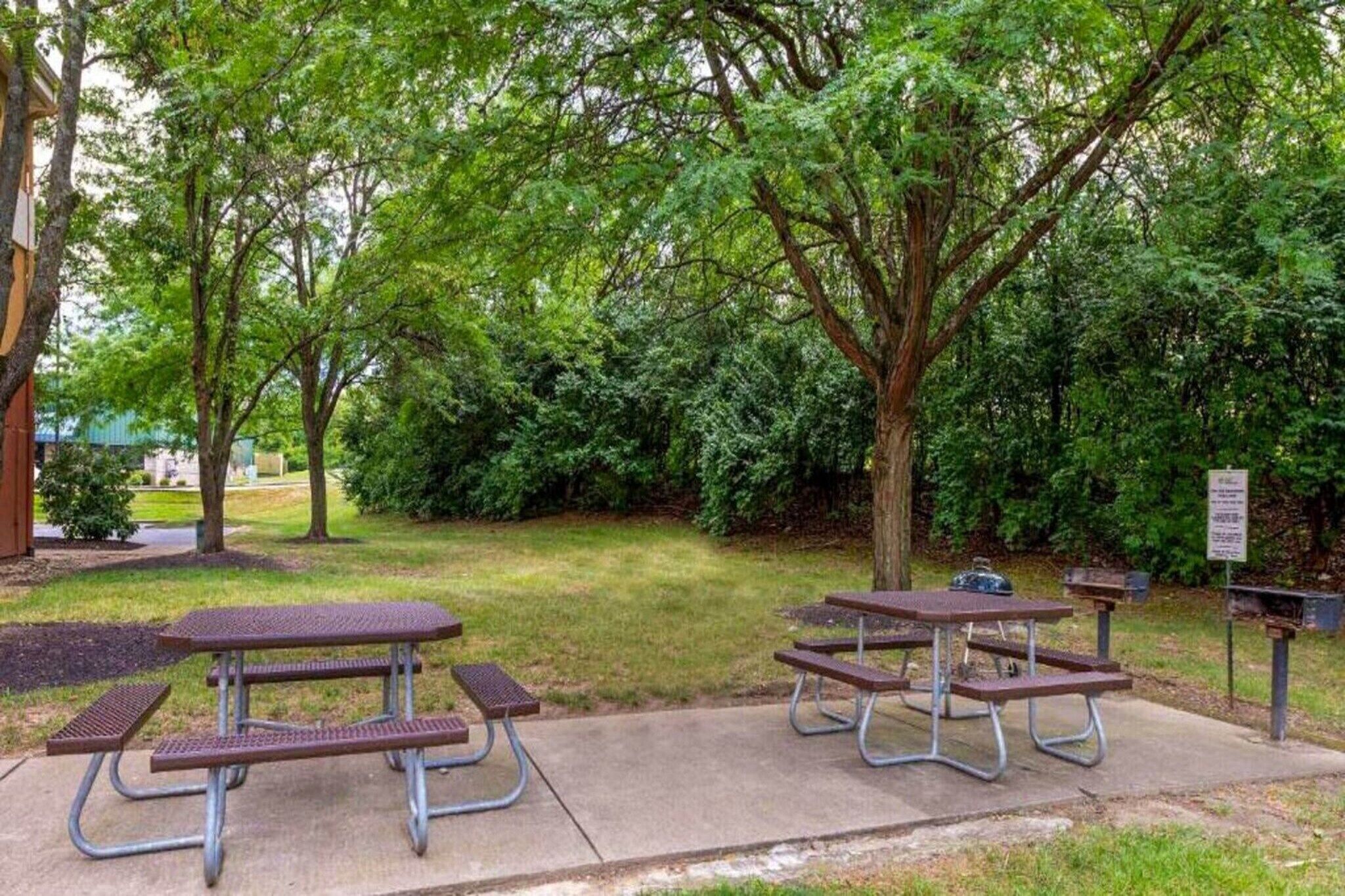 Un parc avec des tables de pique-nique et un panneau d’information.
