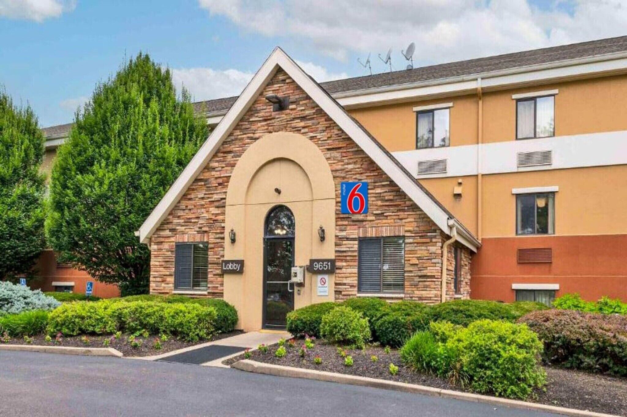 Un hôtel avec une façade en pierre, un hall d’entrée et un parking.