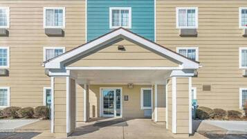 A multi-story building with a central entrance, air conditioning units, and a wheelchair-accessible ramp.