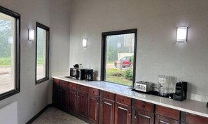 Eine Küche mit Mikrowelle, Toaster und Kaffeemaschine auf der Arbeitsplatte, Holzausbau und einem Fenster mit Blick auf einen roten Wagen draußen.