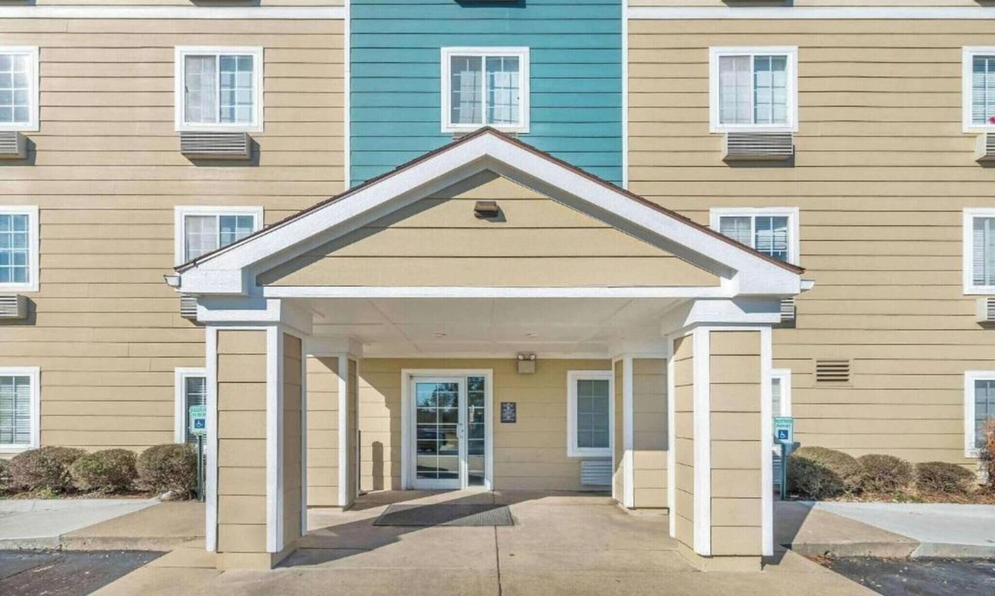 A multi-story building with a central entrance, air conditioning units, and a wheelchair-accessible ramp.
