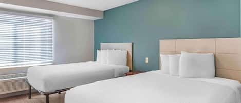 Une chambre d’hôtel avec deux lits, une fenêtre avec des stores, un radiateur mural et un luminaire au plafond.