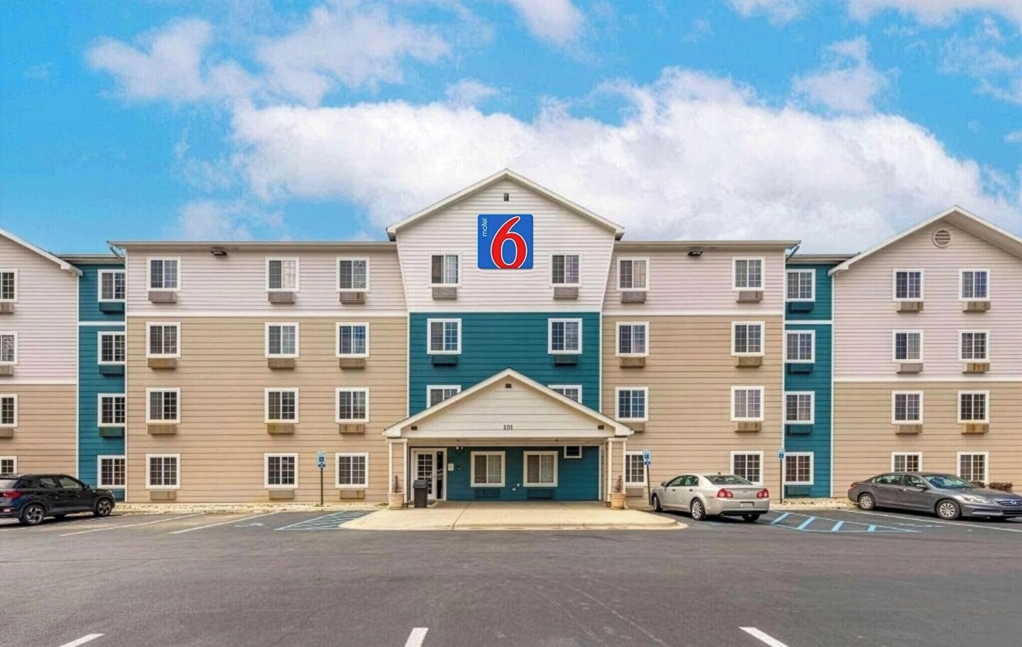 A motel with a central entrance, multiple floors, and a parking lot.