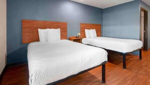 Une chambre d’hôtel avec deux lits, des têtes de lit en bois et un mur bleu.