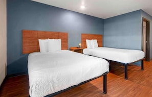 Une chambre d’hôtel avec deux lits, des têtes de lit en bois et un mur bleu.