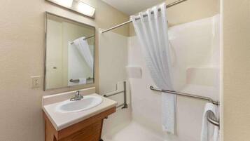 A bathroom with a sink, mirror, and shower.