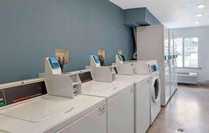 A laundry facility with multiple washing machines and dryers, a control panel, and a window providing natural light. - 2 Full Beds | Non-Smoking, Kitchen (Pelham AL)