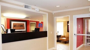 Zona de recepción de un hotel con un cartel de 'WELCOME', mostrador de recepción y un cartel con el número '6'.