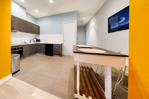 A modern kitchen with grey cabinets, a black dishwasher, and a white countertop. - Serenity Cloud Apartment in Vibrant Footscray (Footscray)