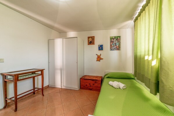A room with a bed, a desk, a wardrobe, and a small chest of drawers.