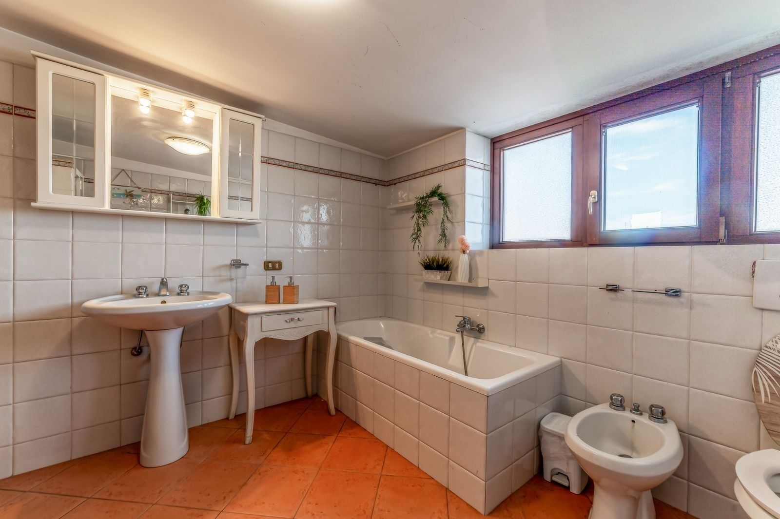 Ein Badezimmer mit Standwaschbecken, Badewanne, Bidet und einem Fenster.