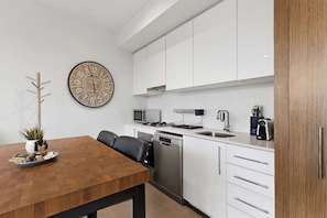 A modern kitchen with white cabinets, a microwave, a dishwasher, and a coffee machine. - City-View 1-Bed Apartment Near Central Park (Richmond)