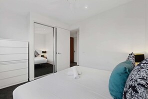 A hotel room with a bed, a wardrobe, and a bathroom visible through an open door. - City-View 1-Bed Apartment Near Central Park (Richmond)