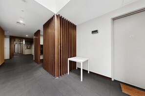 A hallway with a wooden partition, a white table, and a door marked with the number 20. - City-View 1-Bed Apartment Near Central Park (Richmond)