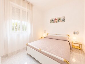 A bedroom with a bed, a window with curtains, a wall-mounted picture, and bedside lamps. - Villa in Santa Maria Del Focallo with 3 bedrooms sleeps 6 (Santa Maria Del Focallo)