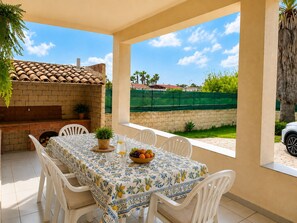 An outdoor patio with a table set for dining, surrounded by chairs, and a brick oven. - Villa in Santa Maria Del Focallo with 3 bedrooms sleeps 6 (Santa Maria Del Focallo)