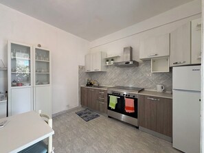 A modern kitchen with a built-in oven, a refrigerator, and a dining area with a table and chairs. - Villa in Santa Maria Del Focallo with 3 bedrooms sleeps 6 (Santa Maria Del Focallo)