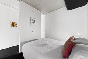 A hotel room with a bed, a door, and two framed pictures on the wall. - Exclusive 1-room apartment in an elevated location, just steps away from shops. (Southbank)
