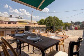 An outdoor dining area with tables set for two, surrounded by chairs, under a green canopy. - La Terrazza in Centro, Genova (Genoa)