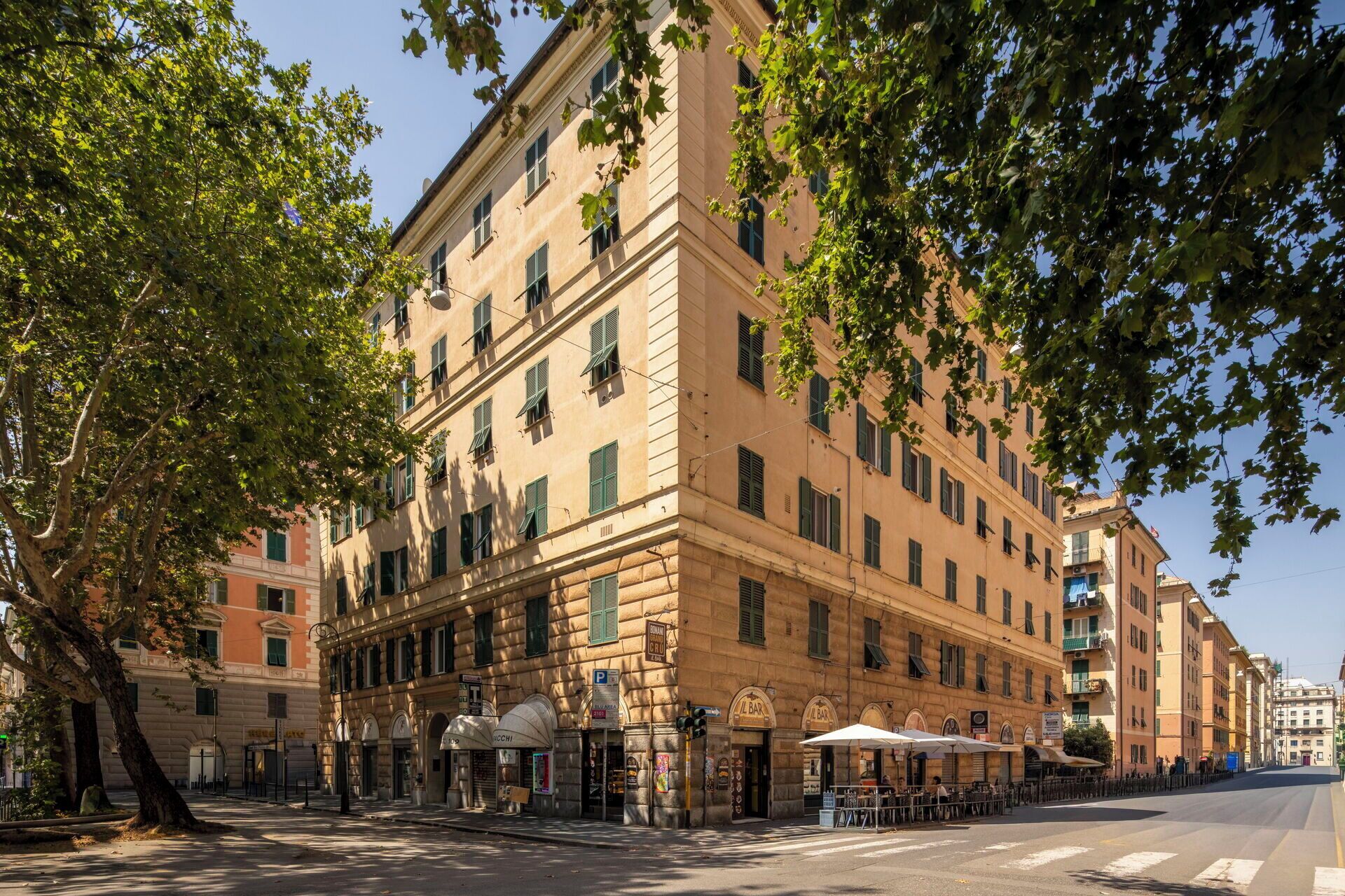 Un immeuble à plusieurs étages, de style architectural classique, comprenant un bar et un restaurant au rez-de-chaussée, avec une terrasse.