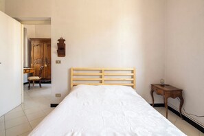 A bedroom with a wooden bed, a small bedside table, and a chair. - La Terrazza in Centro, Genova (Genoa)