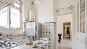 A kitchen with a gas stove, a refrigerator, a sink, and a dining table with chairs. - La Terrazza in Centro, Genova (Genoa)