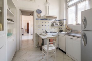 A compact kitchen with white cabinets, a gas stove, a sink, and a window. - La Terrazza in Centro, Genova (Genoa)