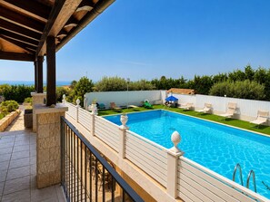 A swimming pool with a clear blue sky, a covered patio area, and a view of the sea. - Villa in Donnalucata with 4 bedrooms sleeps 10 (Donnalucata)