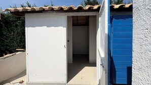 Pieni, yhden huoneen rakennus, jossa on laatoitettu katto ja sininen ovi.