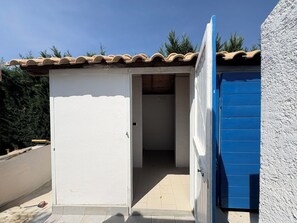 Ein kleines, einräumiges Gebäude mit einem Ziegeldach und einer blauen Tür.