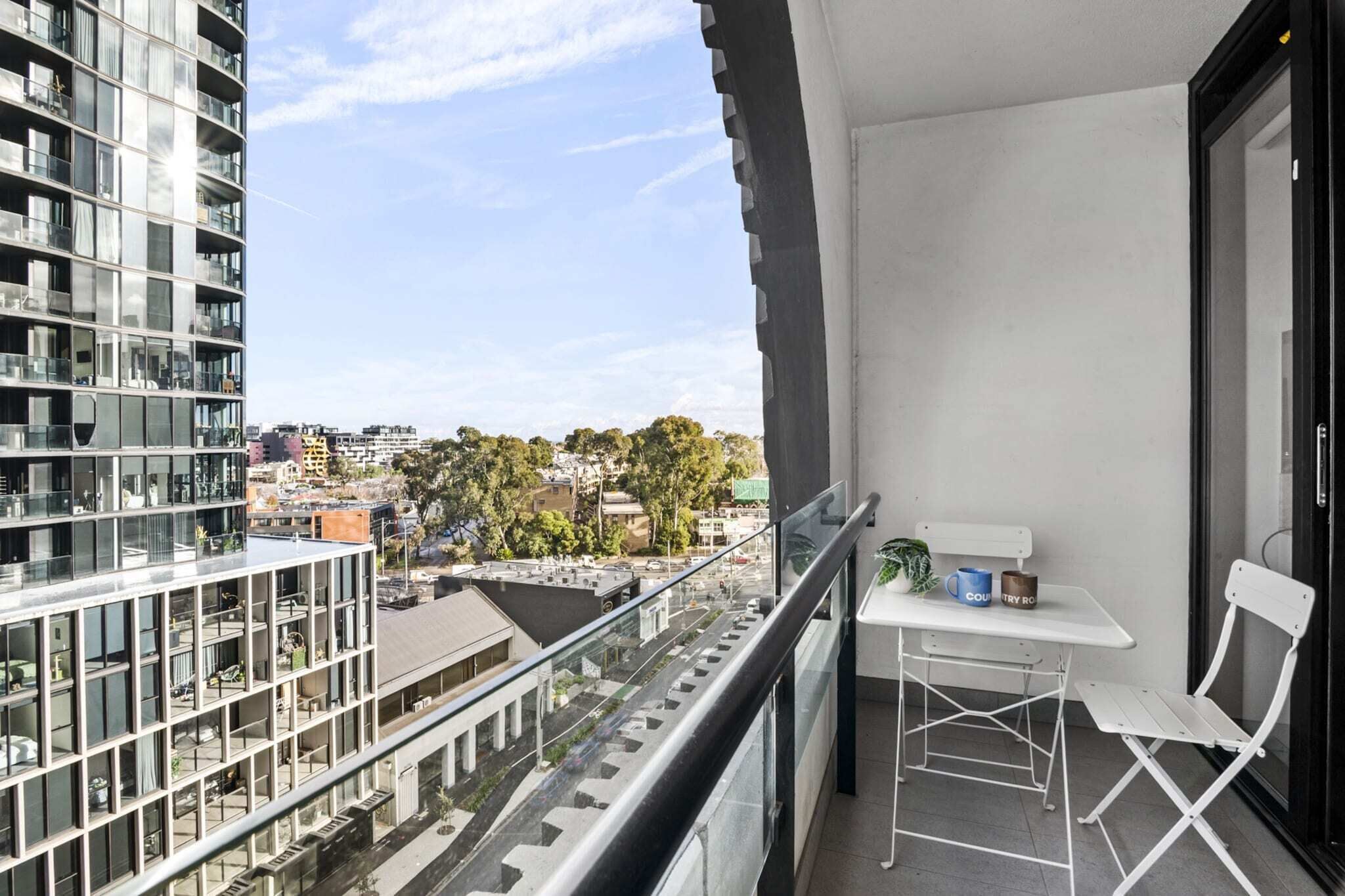 Un balcon avec une table, une chaise et une vue sur le paysage urbain.
