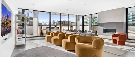 A modern living room with a fireplace, large windows, and a city view.