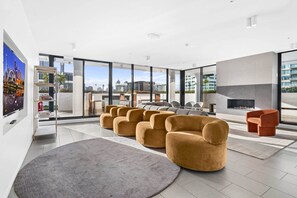 A modern living room with a fireplace, large windows, and a city view. - Bright 2-Bed Apartment Near South Melbourne (South Melbourne)
