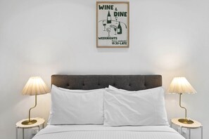 Ein Schlafzimmer mit einem Bett, zwei Nachttischlampen und einem gerahmten Poster an der Wand.