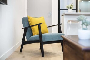 A modern chair with a yellow cushion in a room with a wooden floor and a white wall. - High-Rise 1-Bed Apartment Near Docklands (Melbourne)