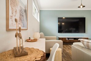 A modern living room with a sofa, a coffee table, and a television. - Luxury Waterfront 5-Bed Family Home Near Mandurah (Halls Head)