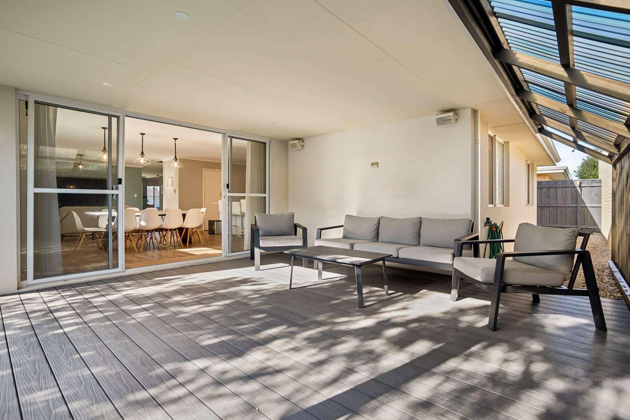 A modern outdoor living area with a sofa, chairs, and a dining table.