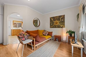 Ein modernes Wohnzimmer mit einer Couch, einem Sessel, einem kleinen Tisch und einem Gemälde an der Wand.