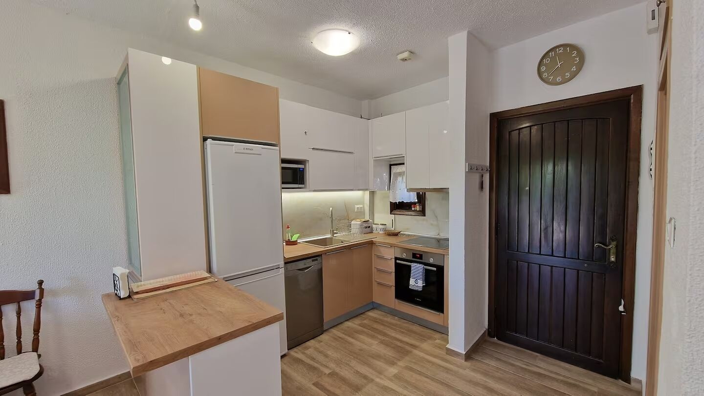 A compact kitchen with a refrigerator, microwave, oven, and dishwasher.