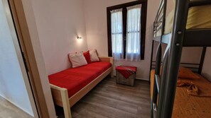 A single bed with a red cover, a bedside table with a red cloth, and a window with curtains. - Halikidiki, Family house to enjoy by the beach (Kalives Polygyrou)