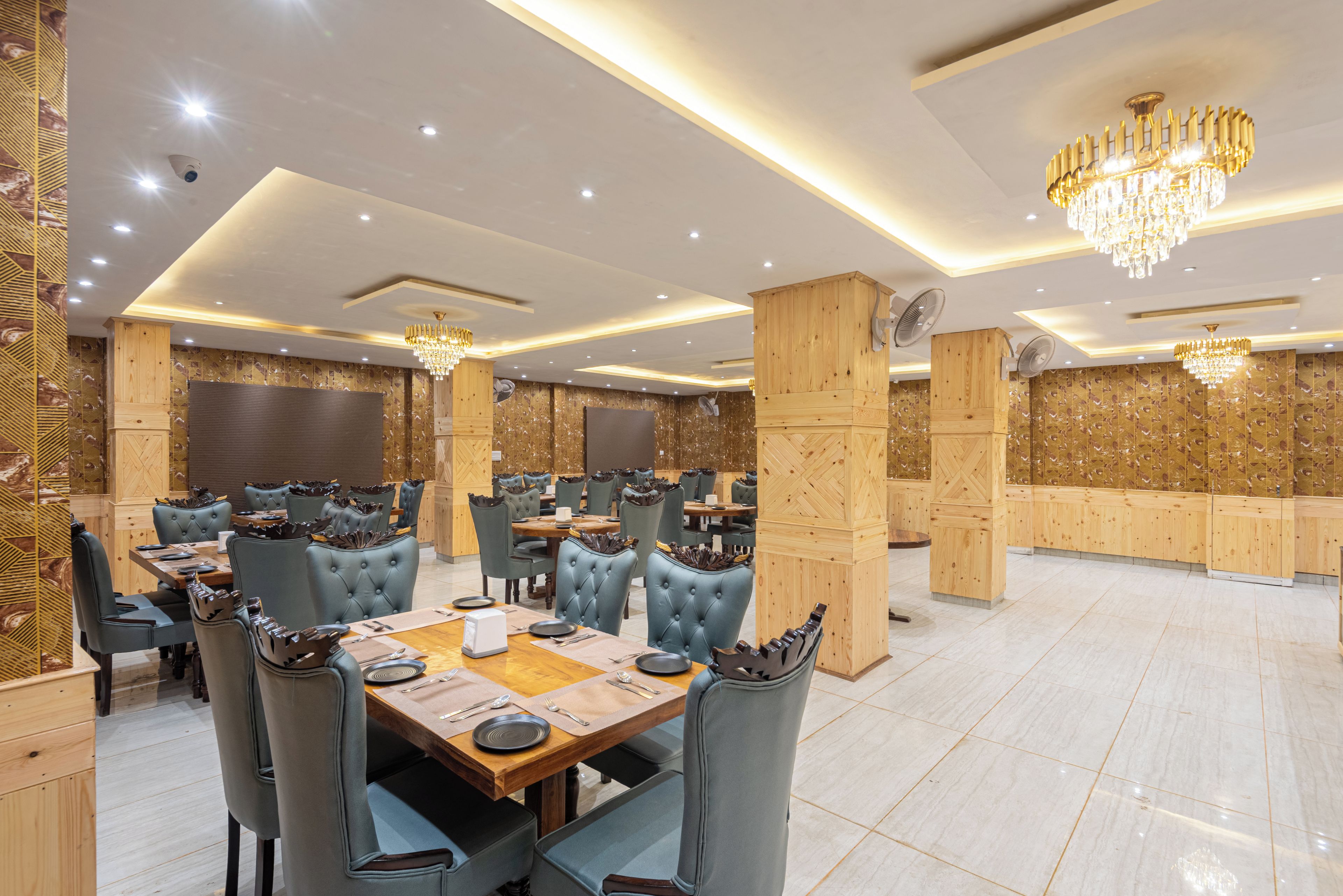 A spacious dining area with multiple tables and chairs, wooden accents, and modern lighting fixtures.