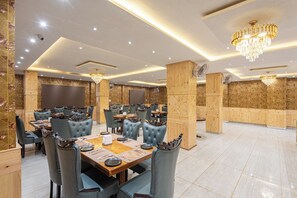 A spacious dining area with multiple tables and chairs, wooden accents, and modern lighting fixtures.