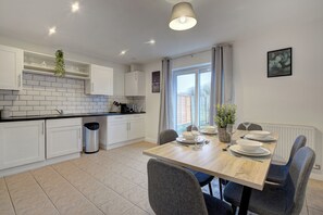 A modern kitchen with white cabinets, a black countertop, and a dining table set for four.