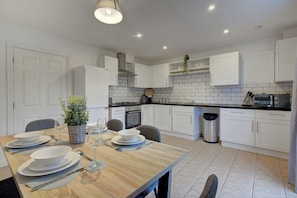 A modern kitchen with white cabinets, a black countertop, and a dining table set for four.