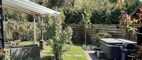 Un jardin avec un patio couvert, un barbecue et une clôture en bois.